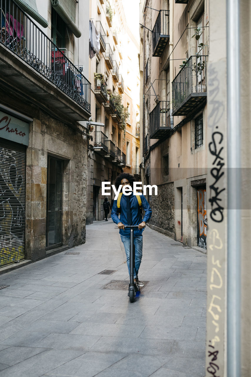 Man with backpack riding on his e-scooter in the city after work, barcelona, spain