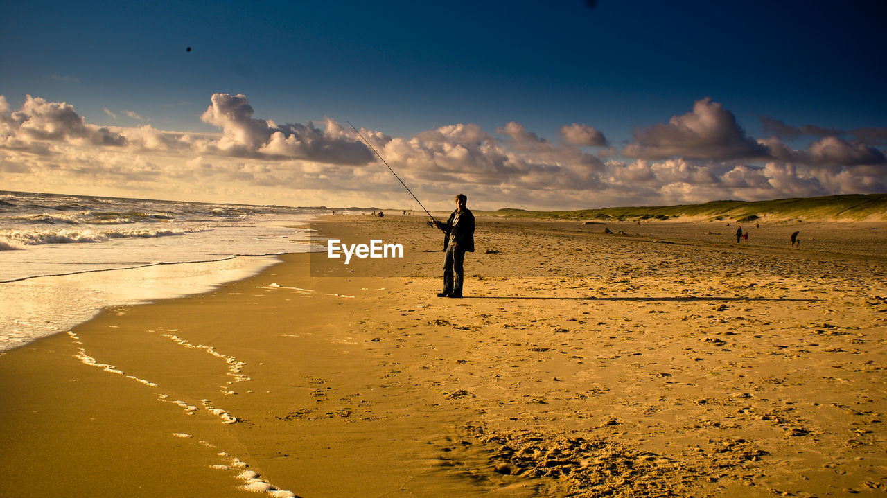 Full length of man fishing while standing at beach