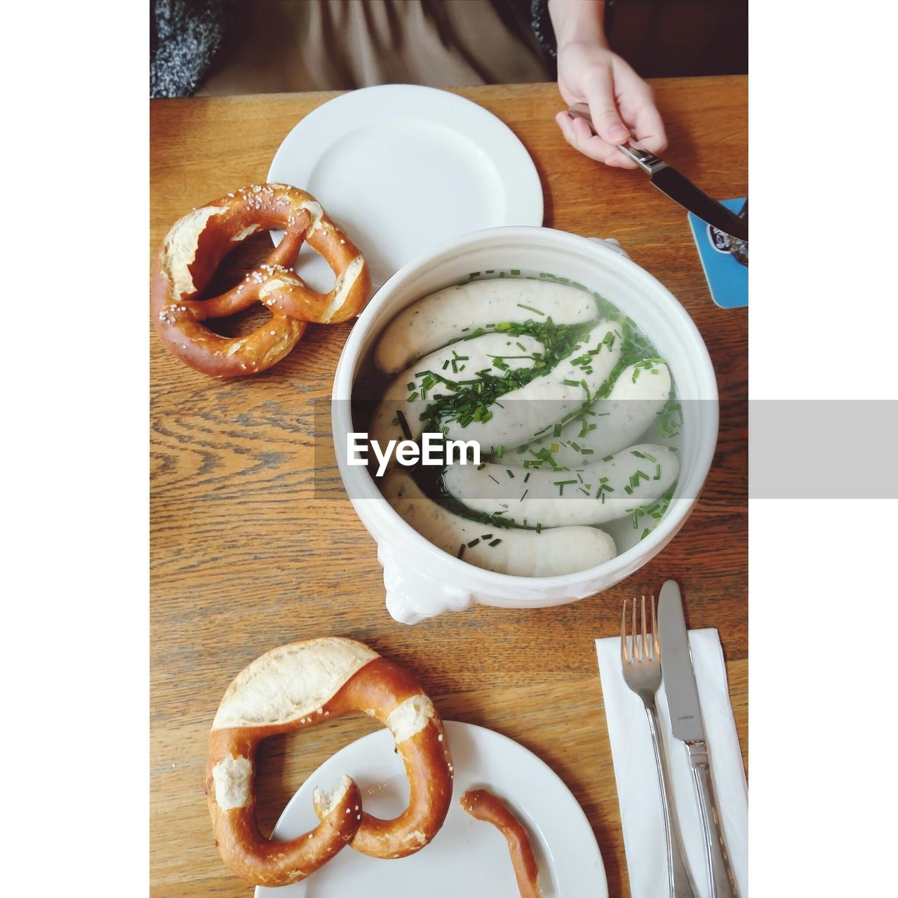 High angle view of woman eating fresh weisswurst and pretzel on table