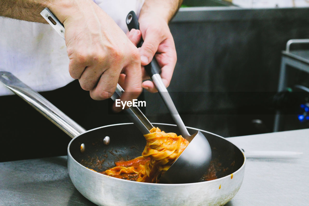 Midsection of male chef preparing pasta in kitchen