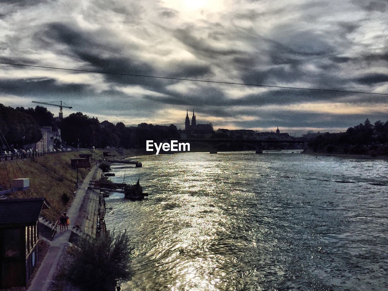 Trees with river below cloudy sky