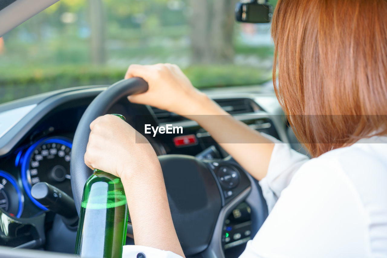 Close-up of woman holding bottle while driving car