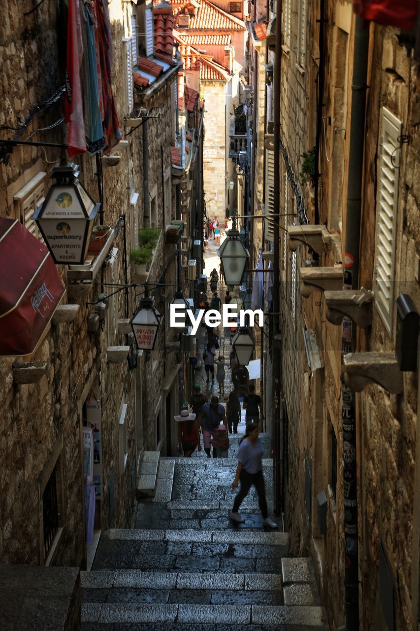 HIGH ANGLE VIEW OF PEOPLE WALKING ON STREET BETWEEN BUILDINGS