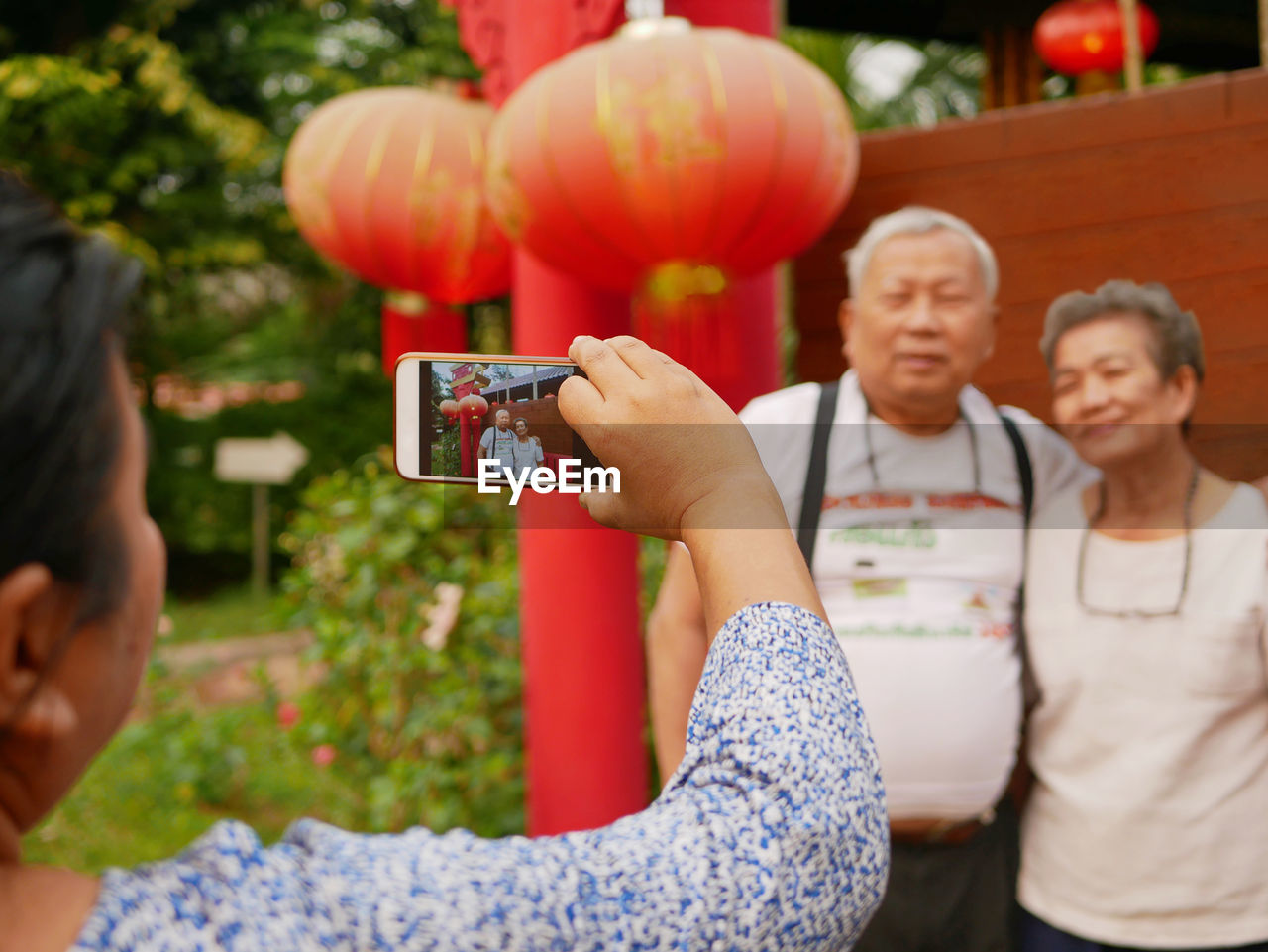 Rear view of woman photographing couple outdoors