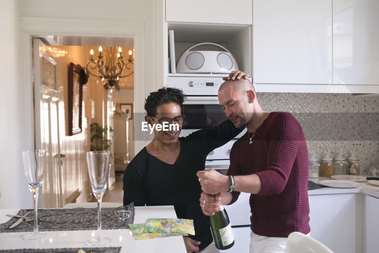 Male couple opening champagne