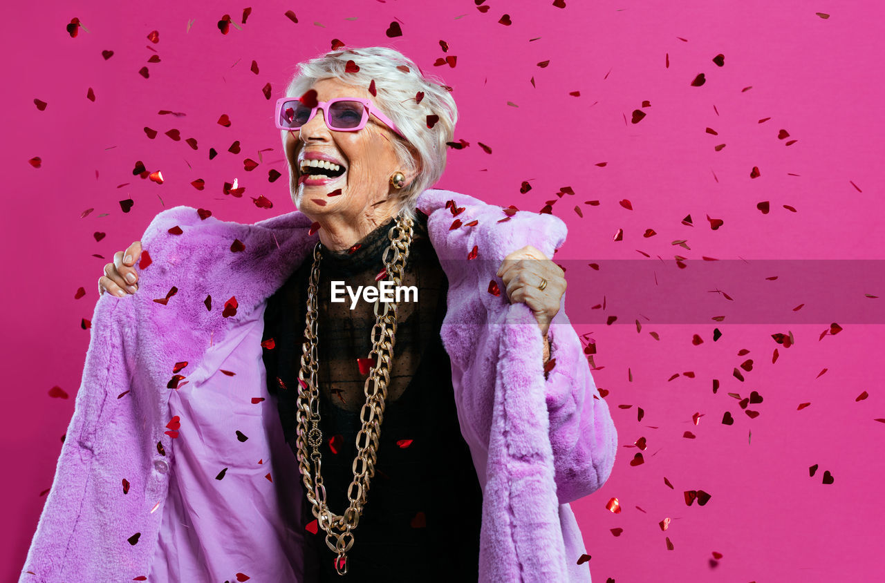 Portrait of young woman standing against blue background