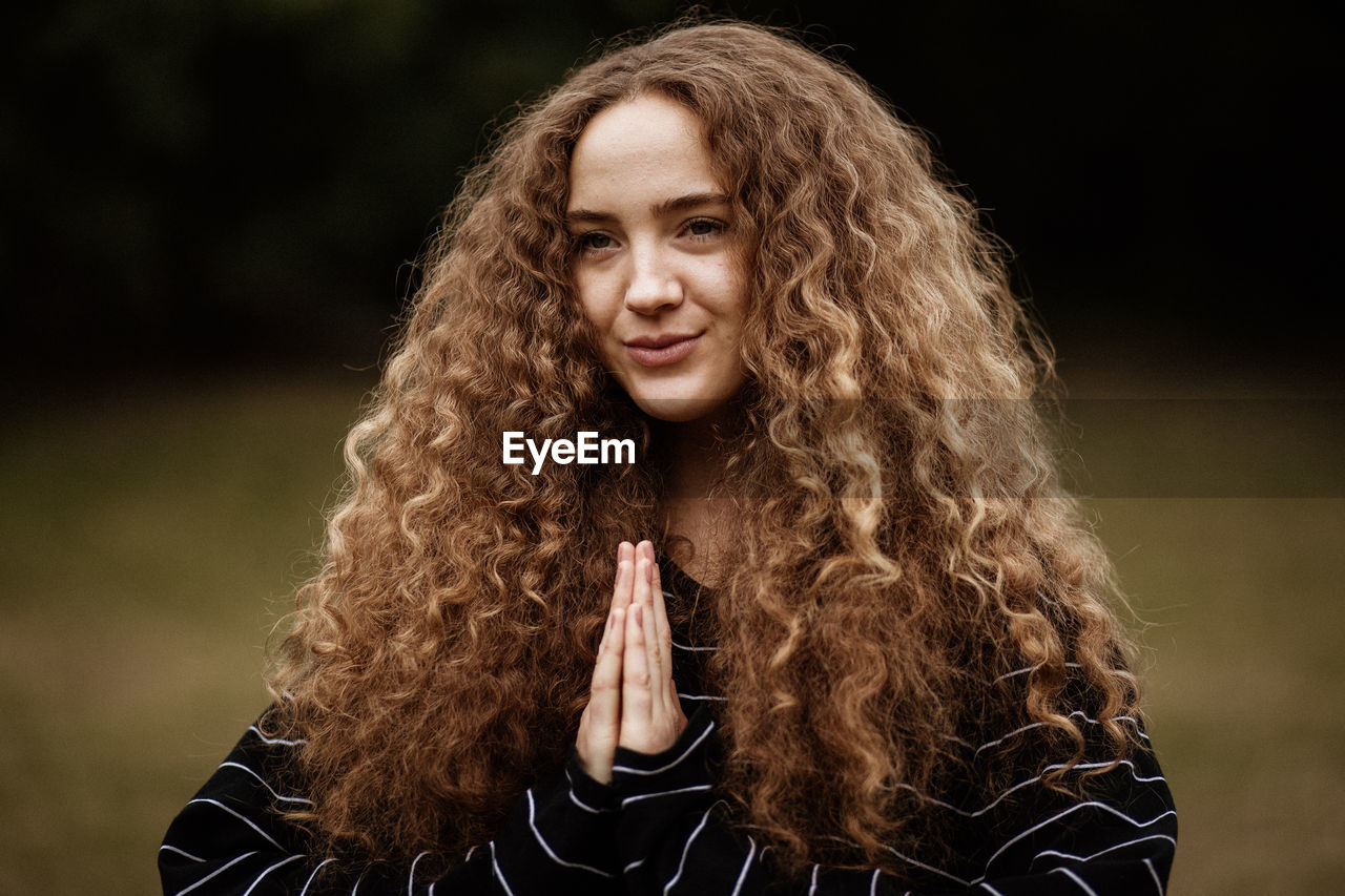 Portrait of a smiling young woman outdoors doing yoga and meditation