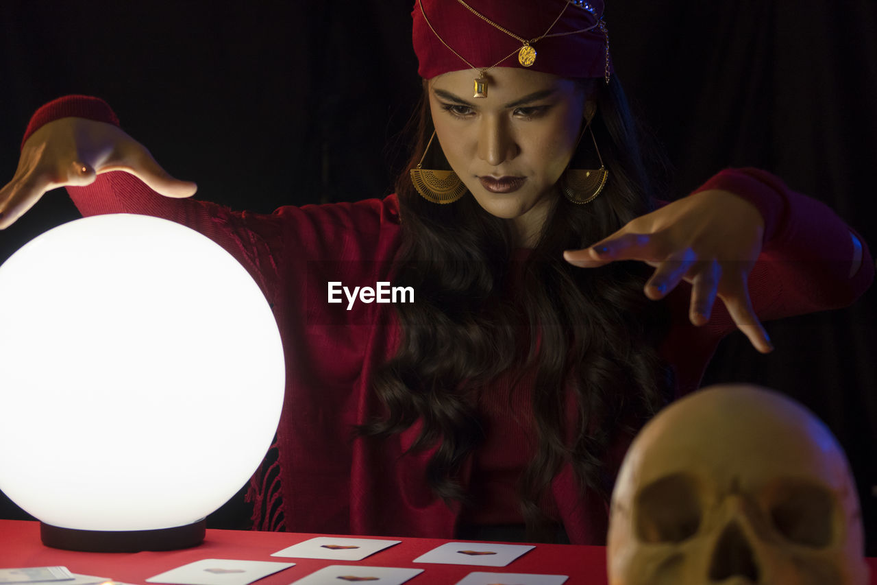 Female fortune teller with sphere and tarot cards at home