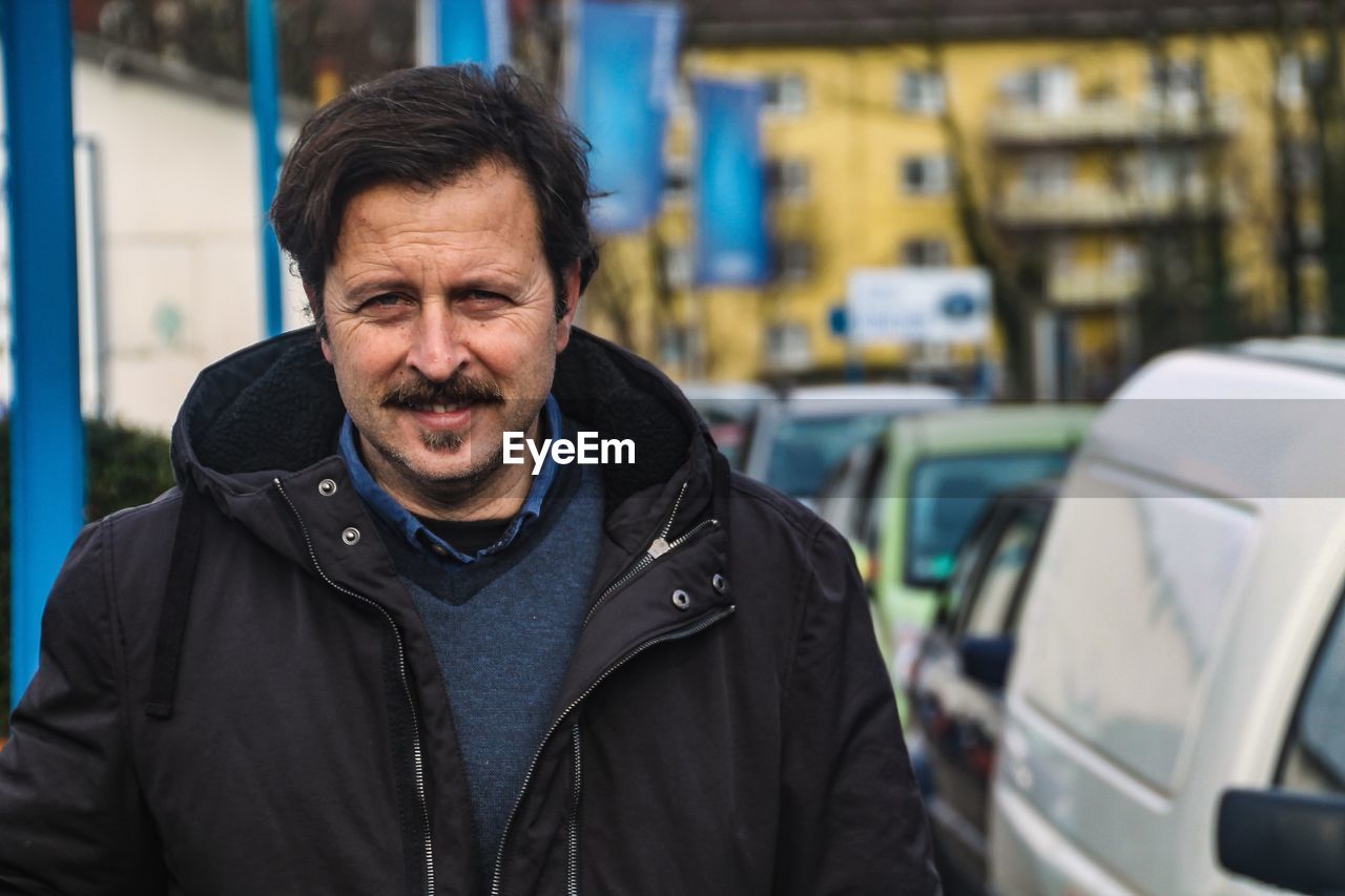 Portrait of smiling mature man wearing warm clothing while standing on street in city