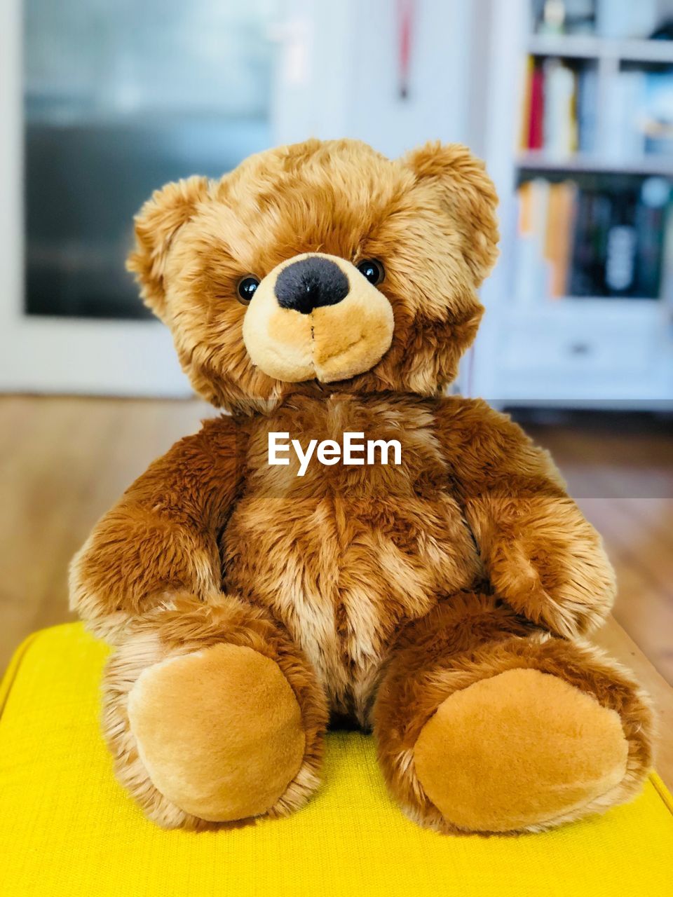 Close-up of teddy bear on yellow seat at home