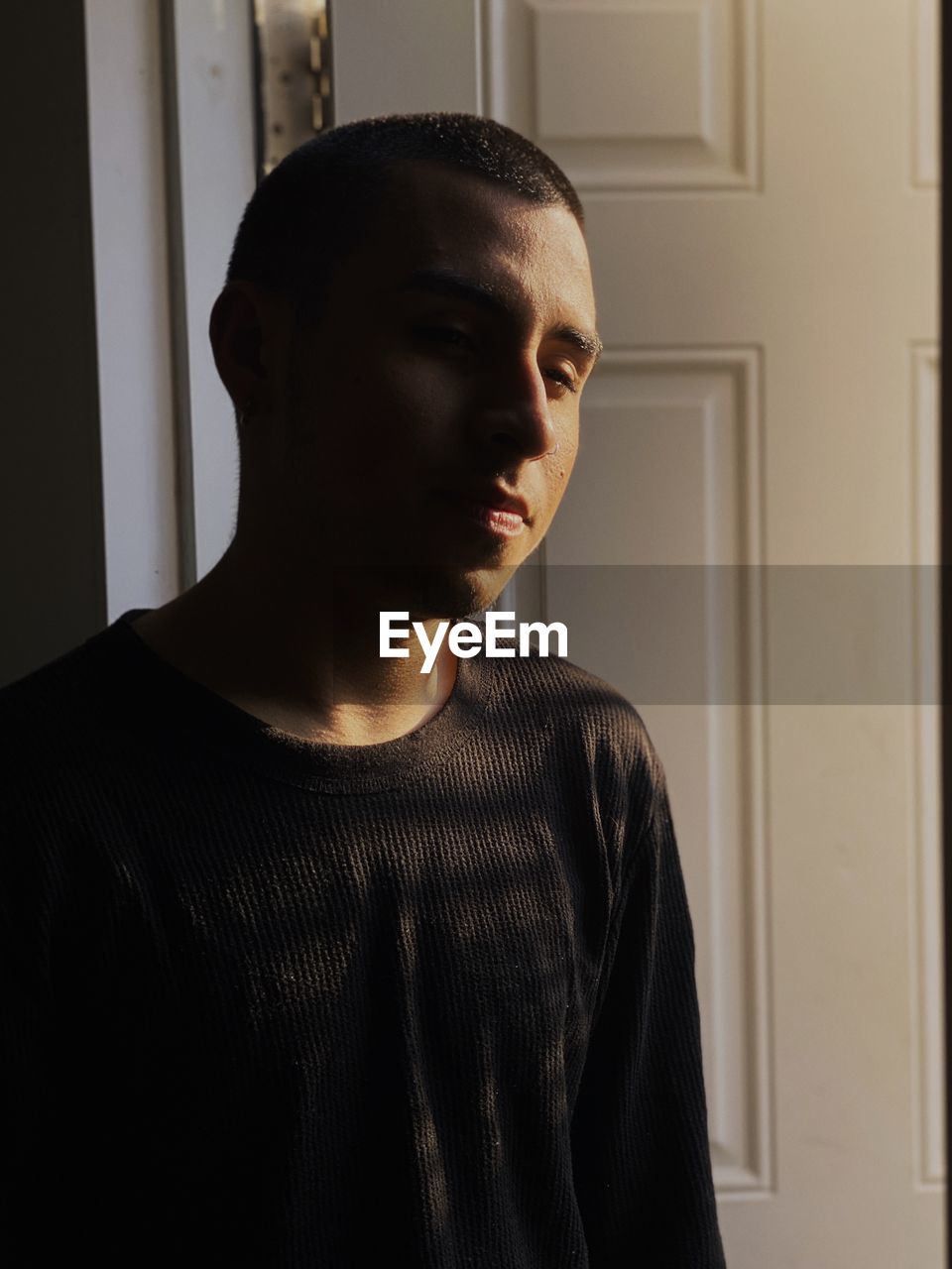 PORTRAIT OF YOUNG MAN STANDING AT HOME