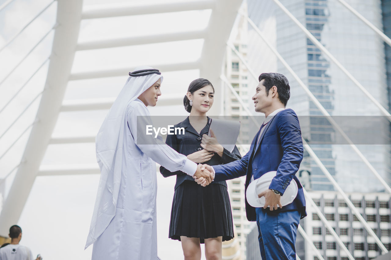 Business people handshaking against metallic structure
