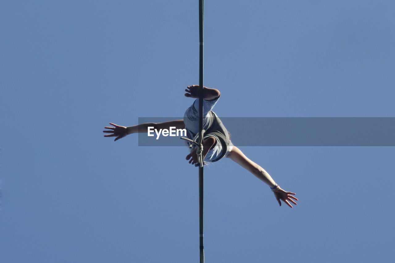 Low angle view of woman standing cable against clear sky