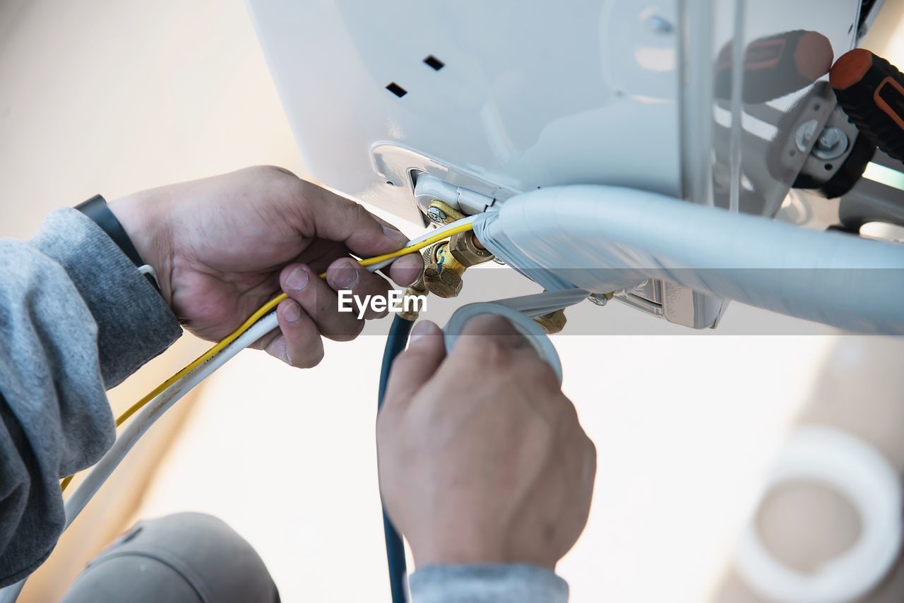 Man is installing wall compressor of air conditioner during hot season