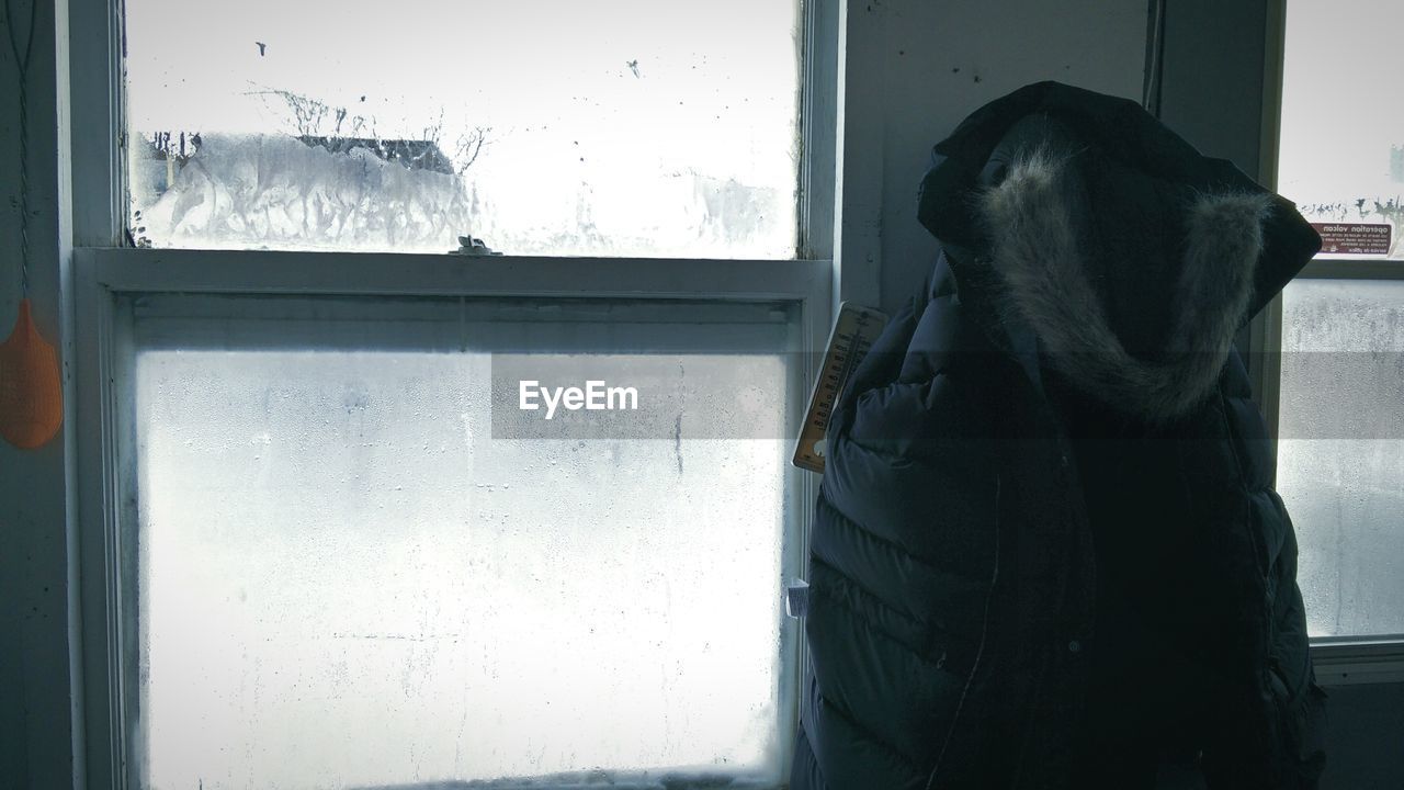 Fur jacket by condensed window at home during winter