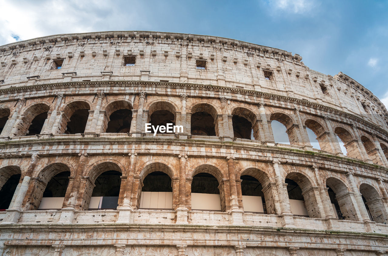 Low angle view of old amphitheater against blue sky