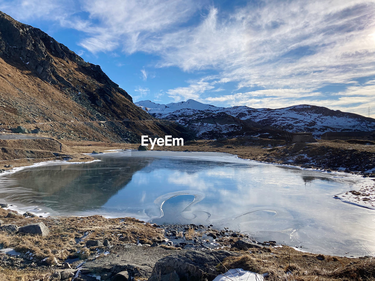 Scenic view of lake by snowcapped mountains against sky, passo del san gottardo, ticino 