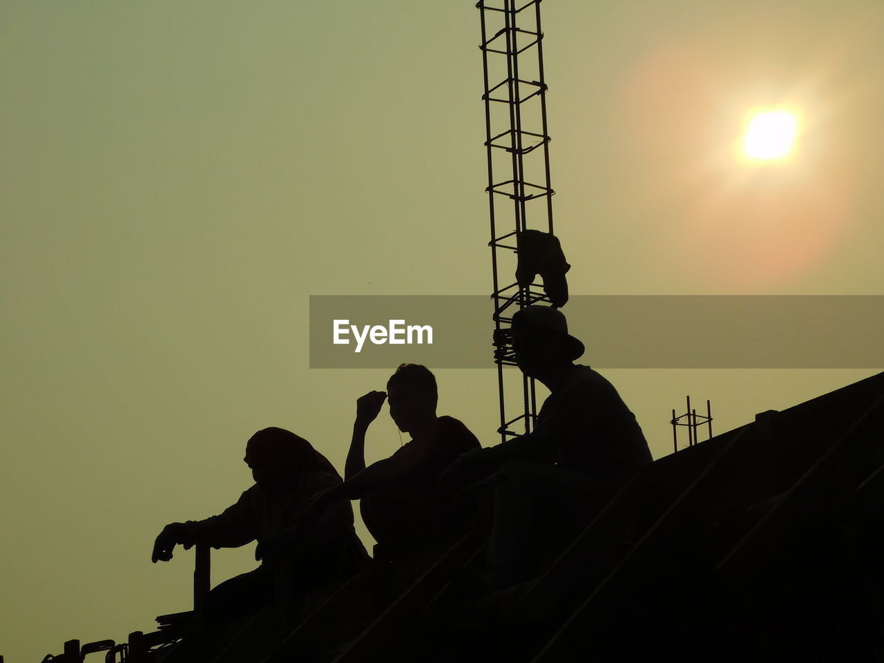 LOW ANGLE VIEW OF MEN WORKING AGAINST SKY