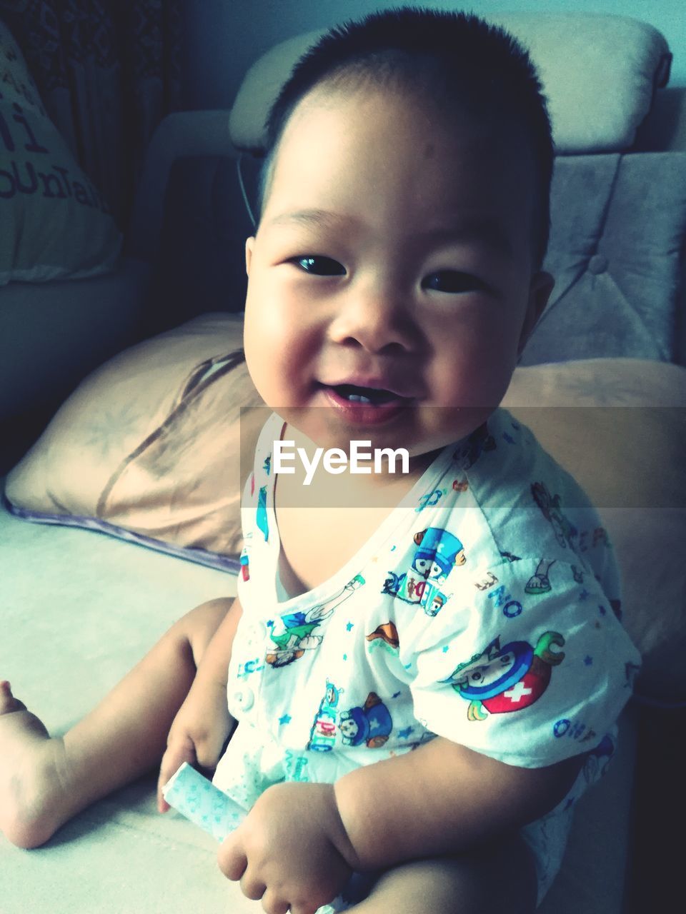 Portrait of baby sitting on bed at home