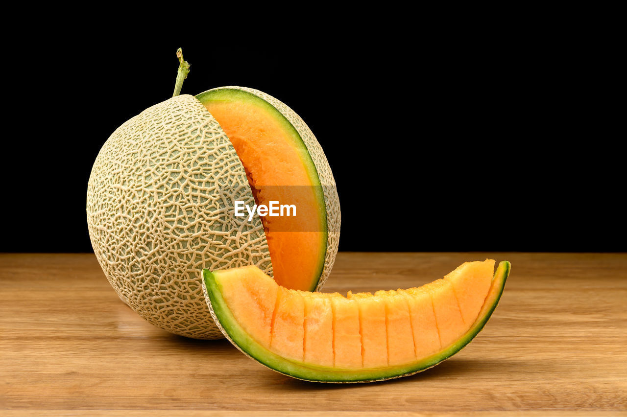 Melon fruit sliced on wooden table with black background