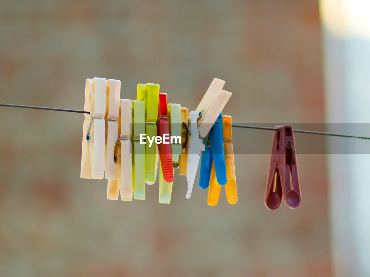 CLOSE-UP OF MULTI COLORED CLOTHESPINS HANGING ON CLOTHESLINE