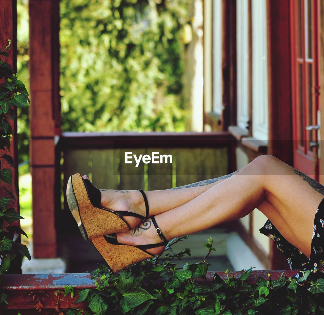 Low section of woman sitting on window