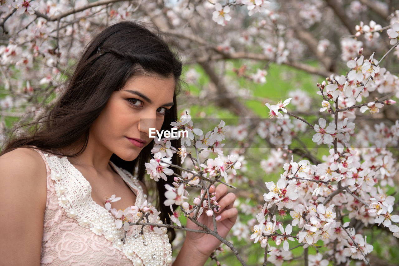 Portrait of young woman with cherry blossoms in spring