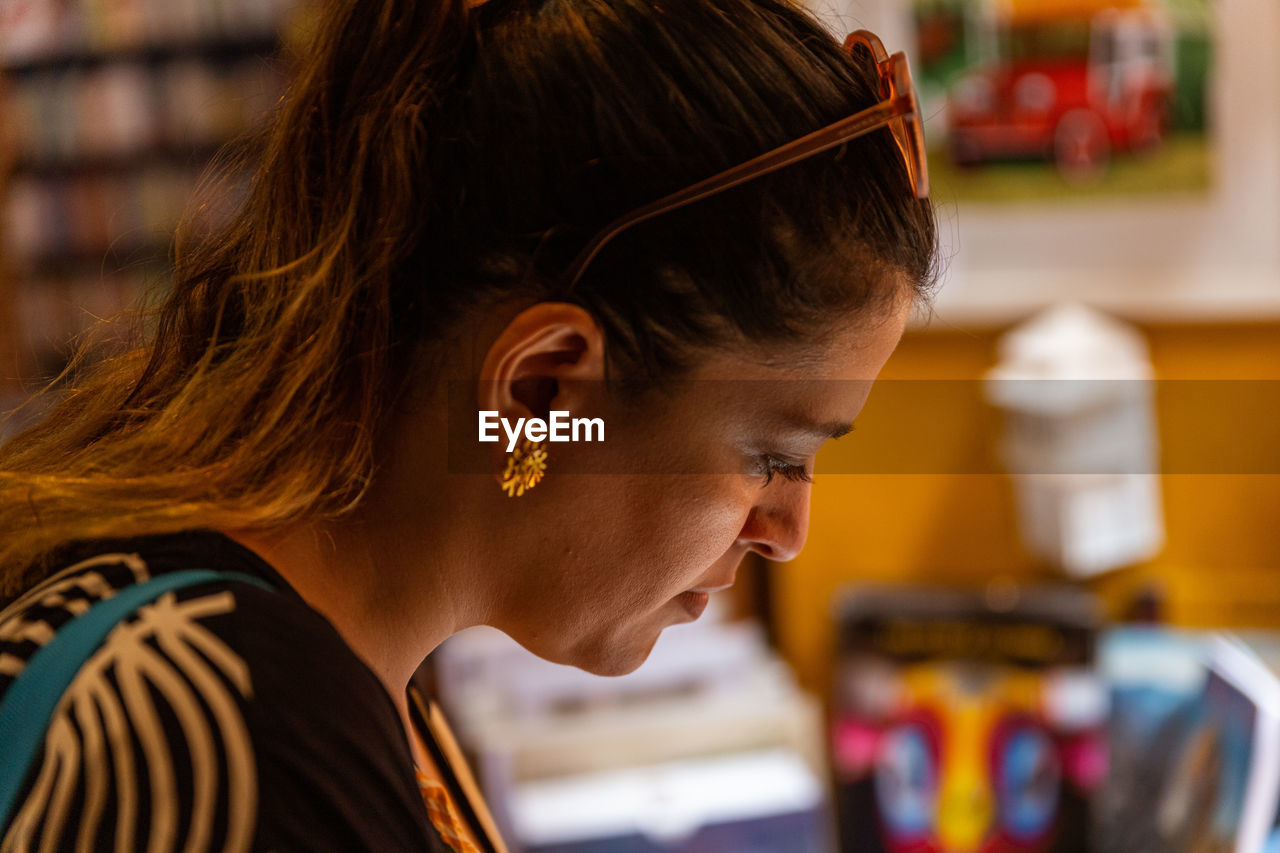 side view of young woman using mobile phone at cafe