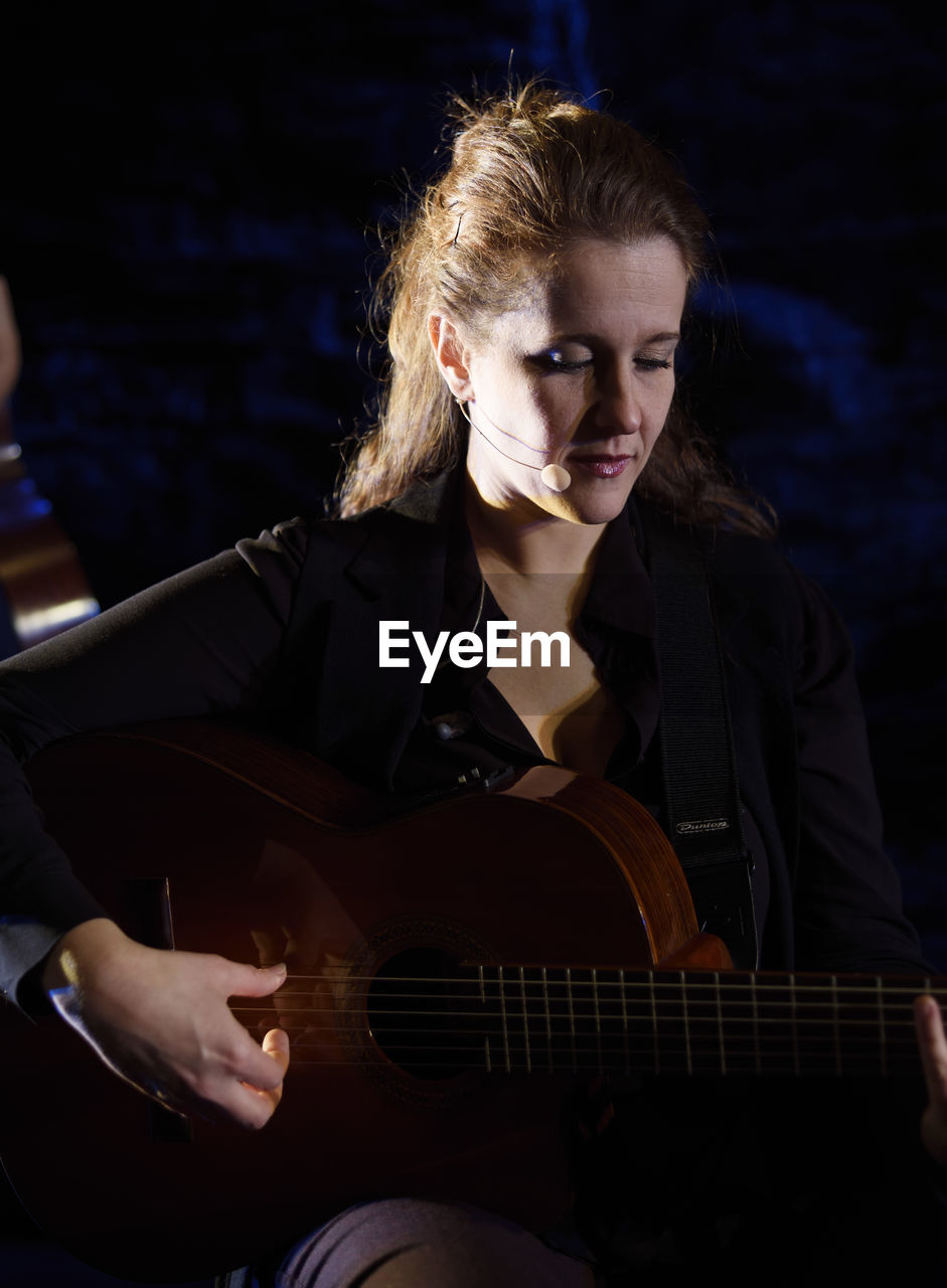 YOUNG WOMAN PLAYING GUITAR WITH CAMERA