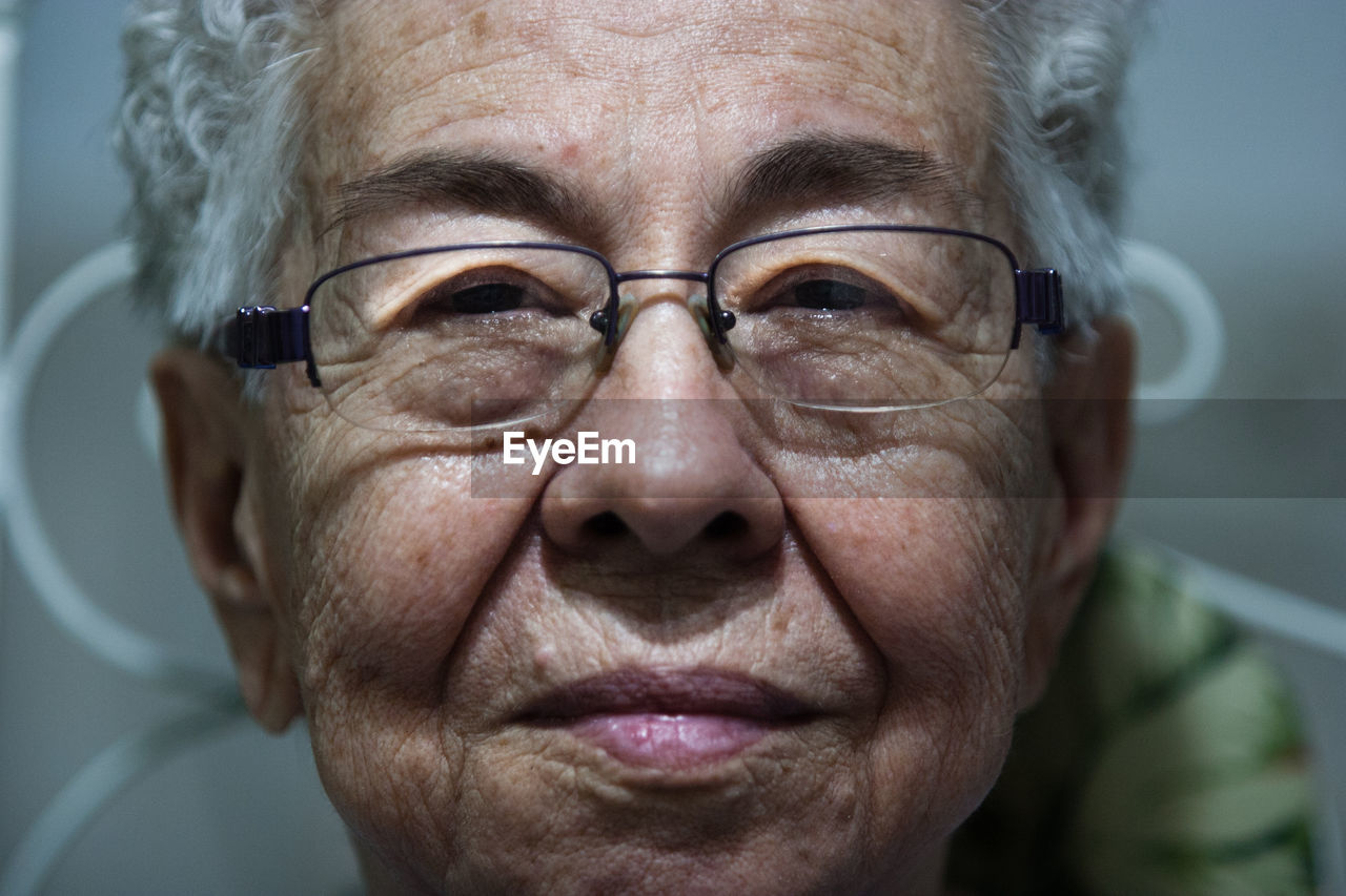 Close-up portrait of senior woman in eyeglasses at home