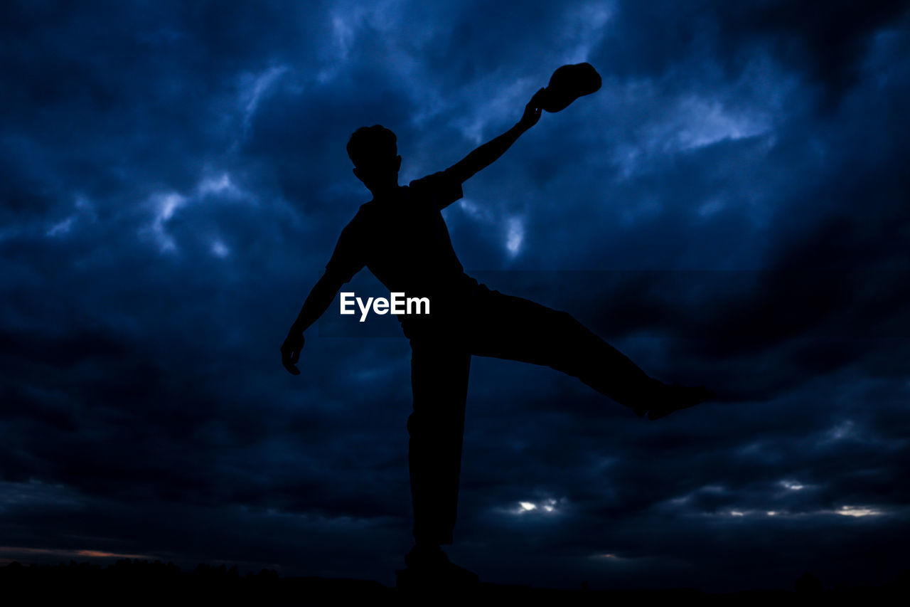 LOW ANGLE VIEW OF SILHOUETTE PERSON AGAINST CLOUDY SKY