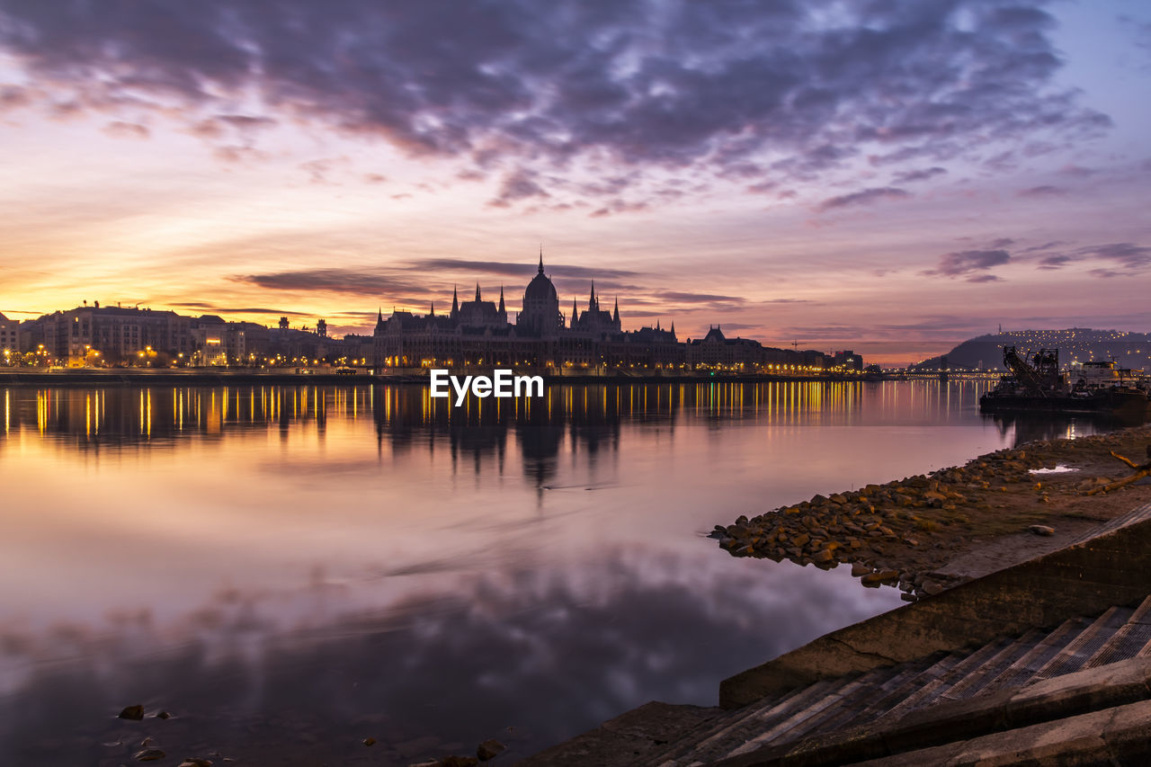 Reflection of buildings in river during sunset