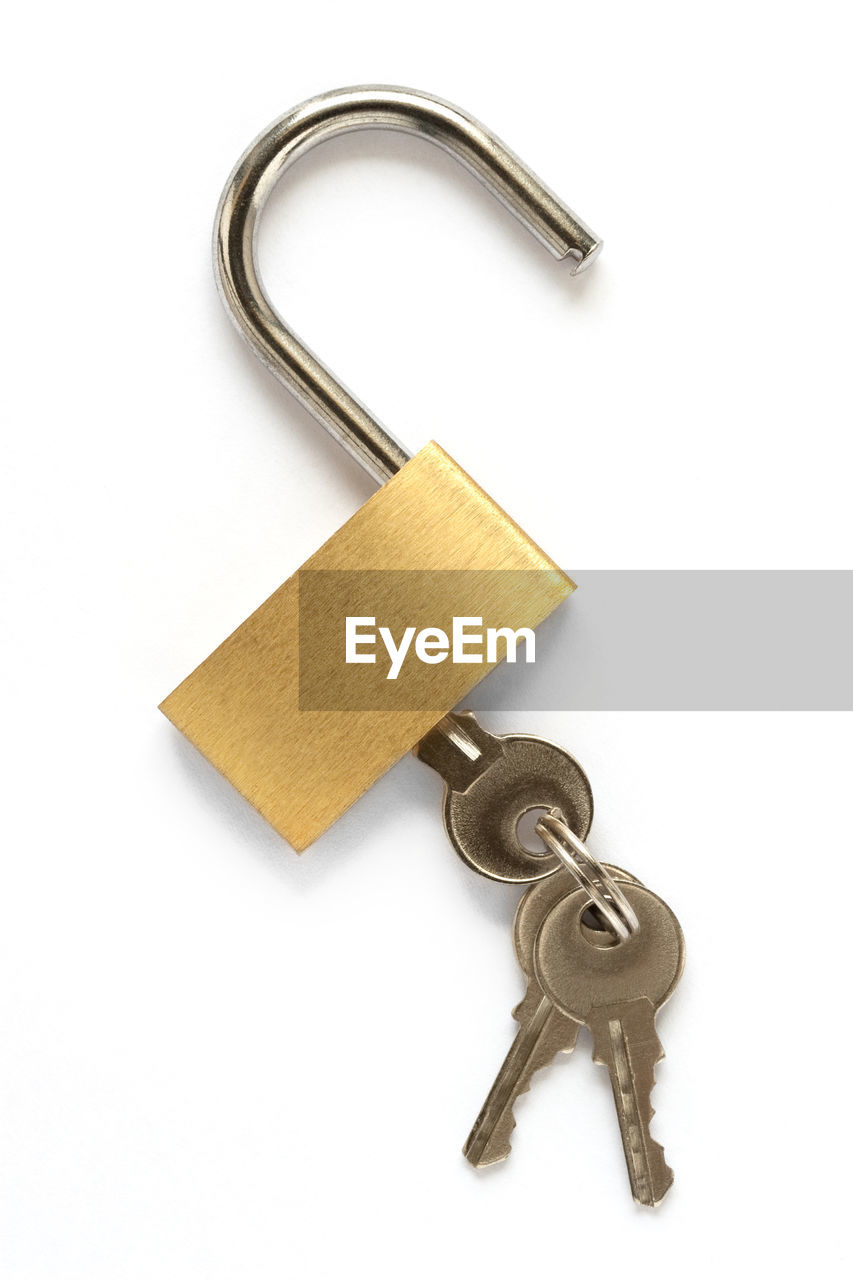 Close-up of key in padlock against white background