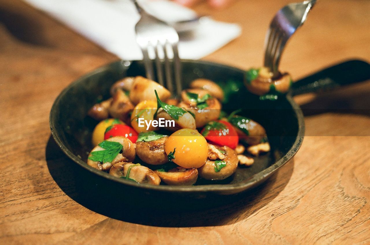 High angle view of cooked mushrooms with cherry tomatoes in pan on table