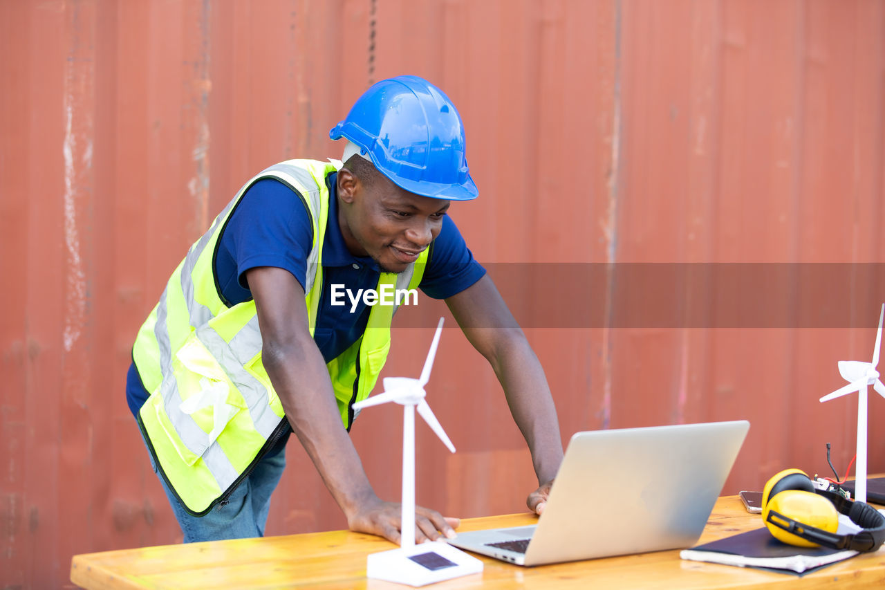 FULL LENGTH OF MAN WORKING WITH LAPTOP