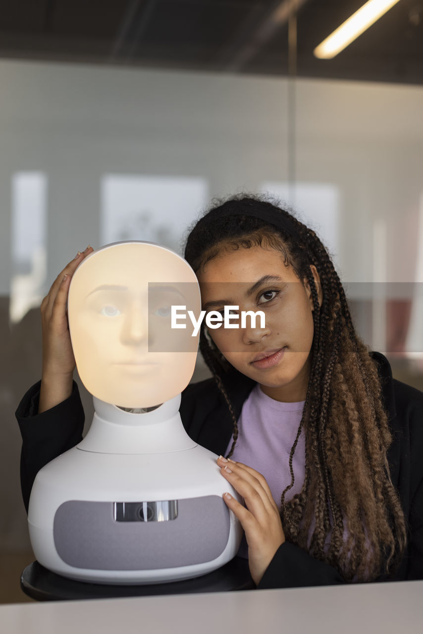 Portrait of young woman with robot voice assistant