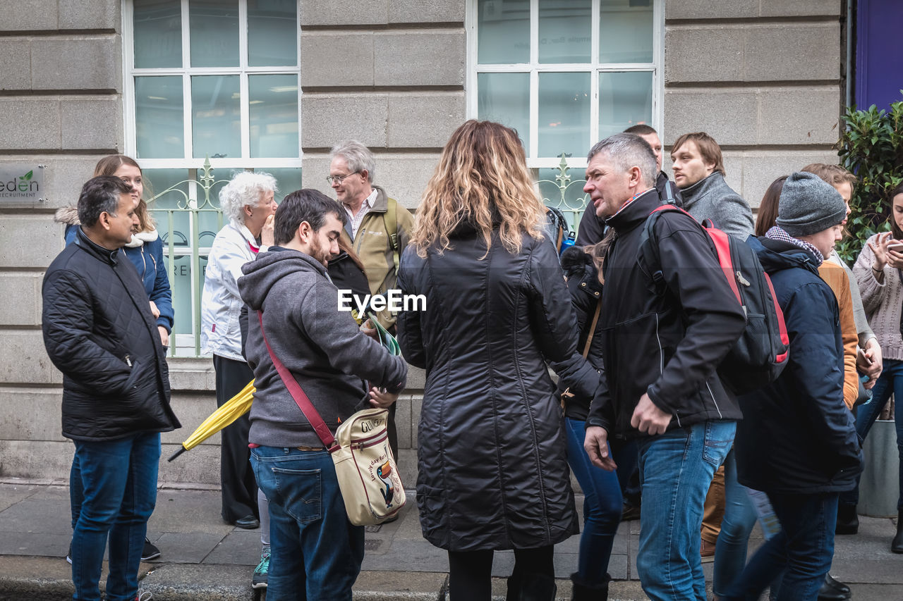 GROUP OF PEOPLE STANDING AGAINST BUILDING