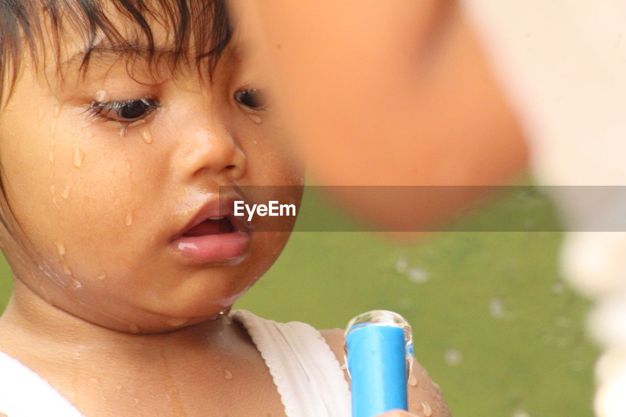 Close-up portrait of cute boy drinking water