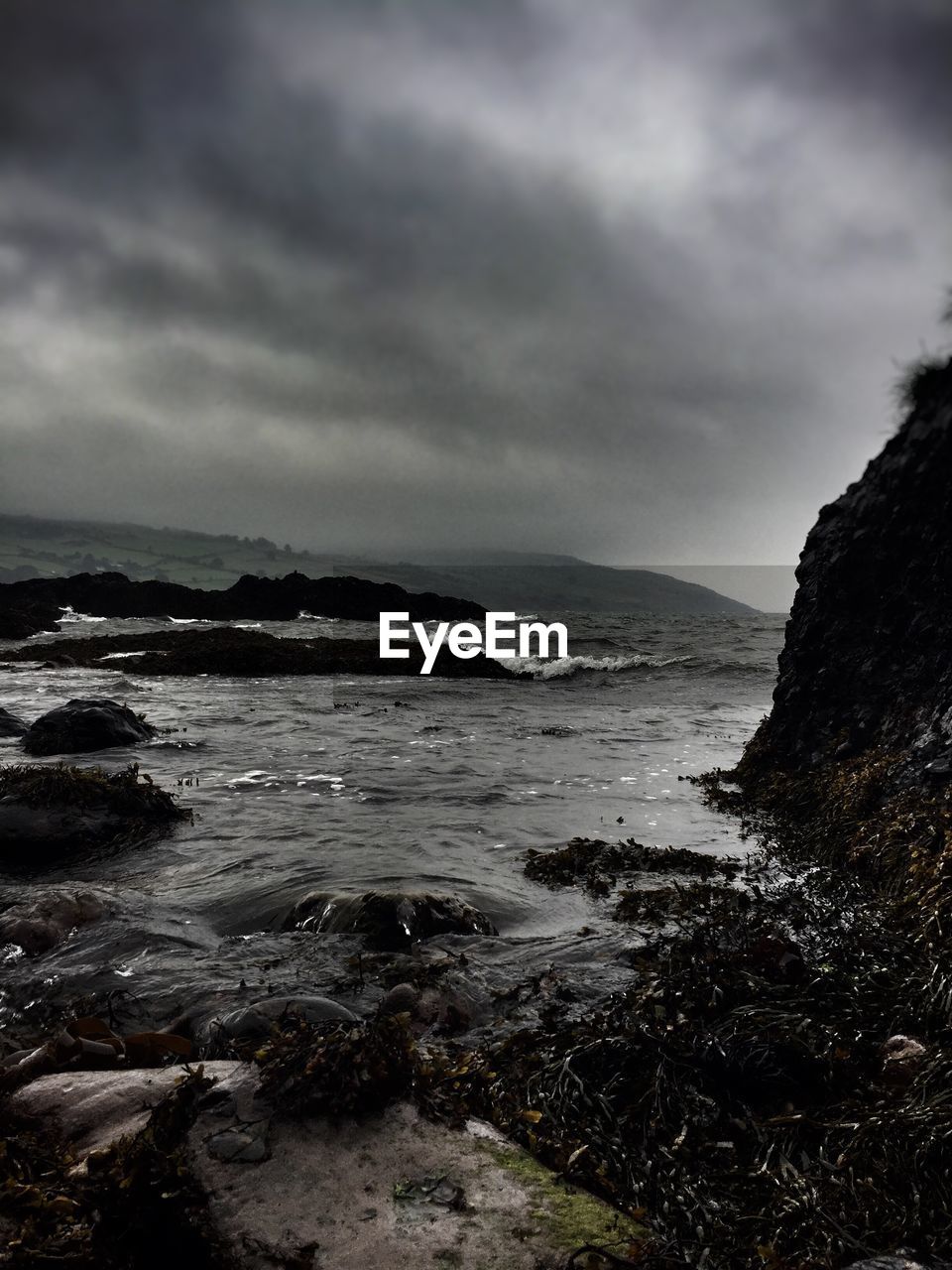 Scenic view of sea and mountains against cloudy sky