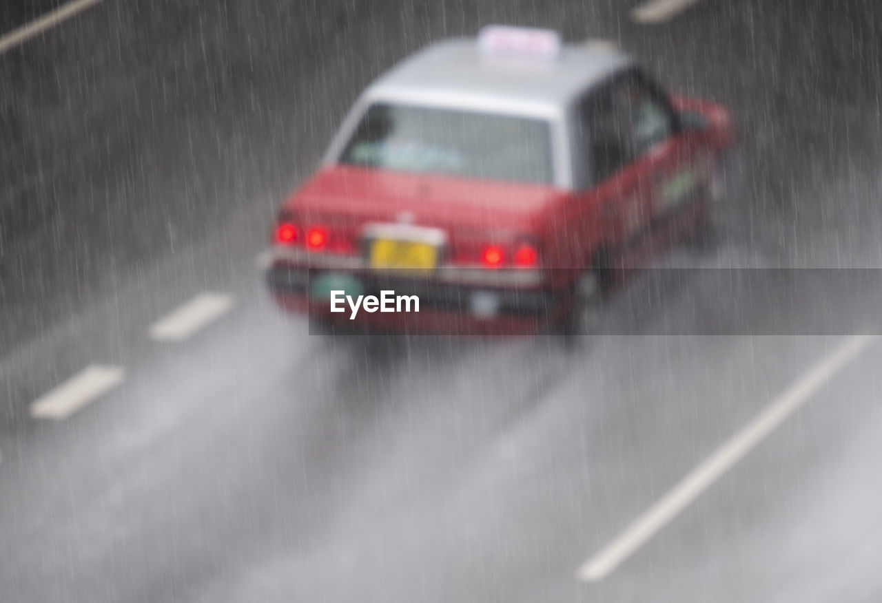 A taxi moves along a rainy road