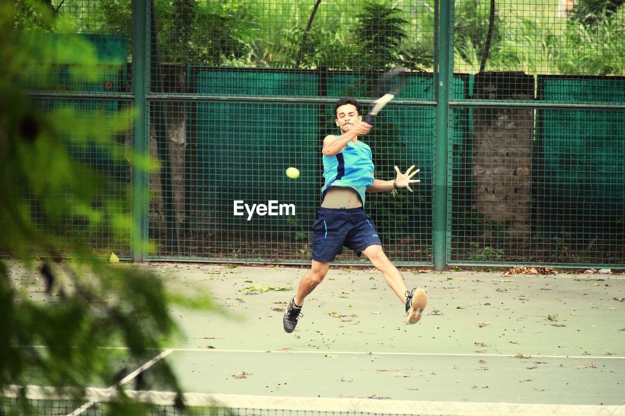 Full length of young man playing tennis