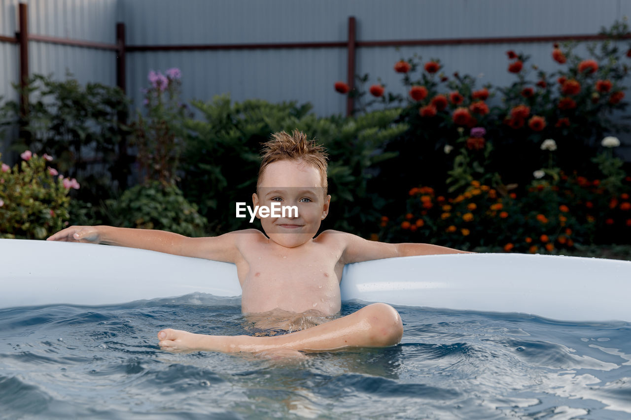 Portrait of smiling boy sitting in wading pool