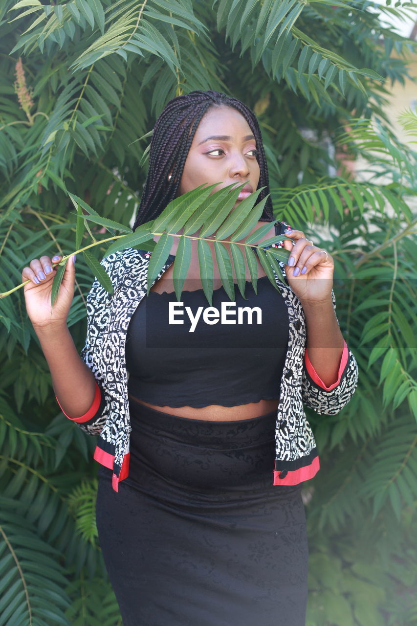 Woman with braided hair standing against plants