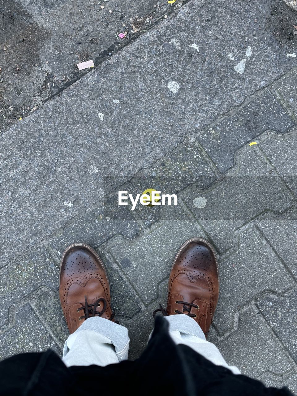 low section, high angle view, men, city, street, footpath, shoe, human leg, standing, one person, day, adult, road, lifestyles, outdoors, clothing, businessman, footwear, human limb, limb, business, directly above, sidewalk, black