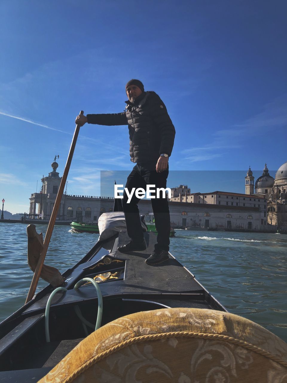 MAN ON BOAT IN CITY AGAINST SKY