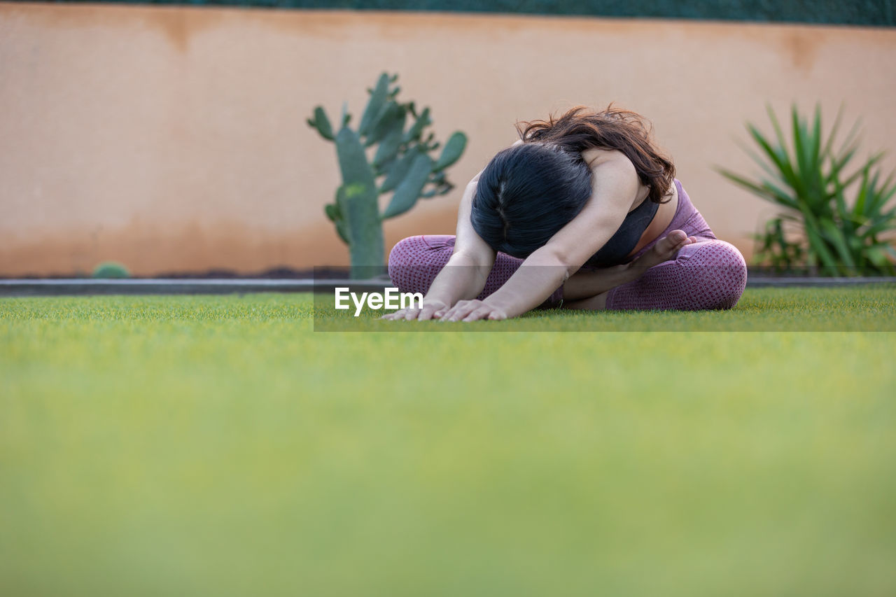 green, one person, grass, women, sports, relaxation, plant, child, adult, selective focus, leisure activity, nature, lifestyles, childhood, young adult, lying down, copy space, brown hair, female, hairstyle, activity, person, emotion, day, outdoors, casual clothing, long hair, surface level, full length, sadness