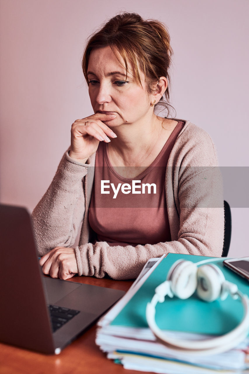 Portrait of young woman using phone while sitting on table