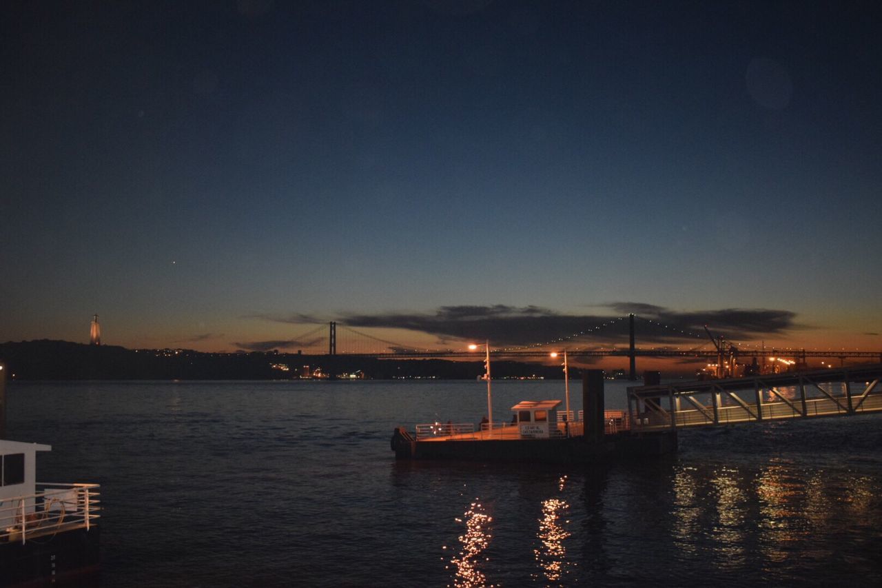 Illuminated pier over sea against sky at night