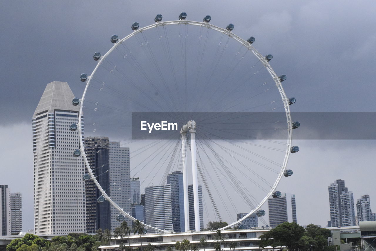 LOW ANGLE VIEW OF FERRIS WHEEL AGAINST BUILDINGS