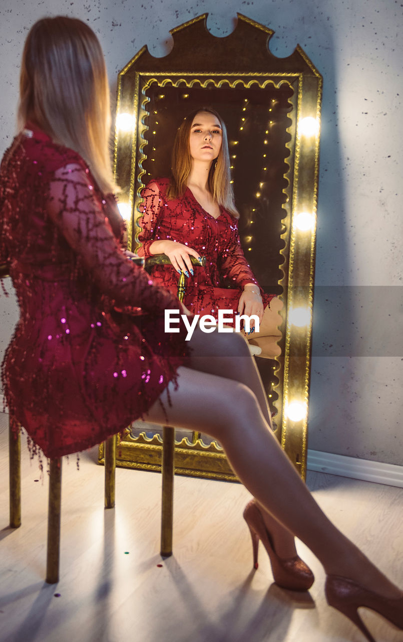Full length of woman sitting on chair looking at mirror